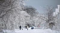 Orang-orang berjalan menyusuri jalan bersalju menyusul badai musim dingin yang melanda sebagian besar Ontario di Fort Erie, Ontario, Kanada, 27 Desember 2022. Kondisi kian buruk dengan suhu yang hampir mencapai minus 45 derajat celcius. (Nick Iwanyshyn/The Canadian Press via AP)
