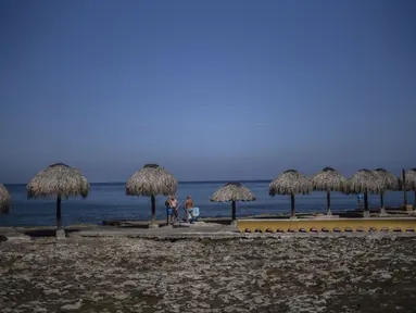 Turis berdiri di sepanjang tepi pantai di Havana, Kuba, pada 2 Maret 2021. Kepulauan Karibia memburu pengunjung untuk menggerakkan kembali roda ekonomi yang terhenti di salah satu kawasan di dunia yang sangat bergantung dengan sektor pariwisata. (AP Photo/Ramon Espinosa)