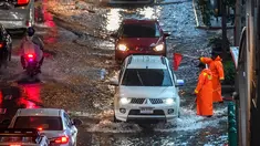 Petugas keamanan mengatur lalu lintas di jalan yang banjir saat hujan deras di Bangkok (23/9/2020). (AFP/Mladen Antonov)