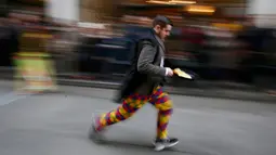 Seorang peserta berlari membawa wajan berisi pancake saat ikut ambil bagian dalam acara tahunan Great Spitalfields Pancake Race untuk mengumpulkan uang bagi Ambulan Udara London di Inggris, Selasa (9/2). (REUTERS/Stefan Wermuth)