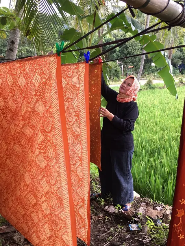 Dalmini menjemur batik-batik yang sudah selesai melalui proses pewarnaan.