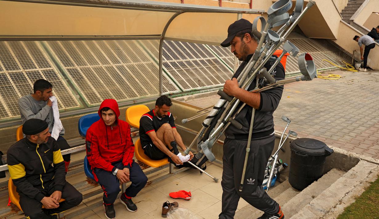 Seorang ofisial tim menyiapkan kruk menjelang pertandingan final kejuaraan lokal sepak bola korban amputasi antara Al-Jazeera melawan Al-Abtal yang diselenggarakan oleh Komite Palang Merah Internasional (ICRC), di tengah pandemi COVID-19, di Kota Gaza, (18/3/2021). (AFP/Mohammed Abed)