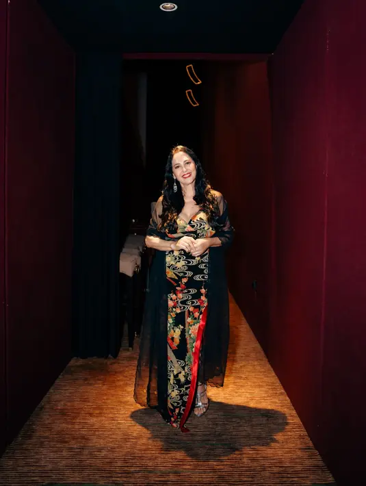 Meriam Bellina sebagai mamah Diah, tampak elegan dengan dress hitam dengan motif penuh nuansa kehijauan. Dress tersebut ia padukan bersama mesh long outer. [Dok/Gampang Cuan Film]