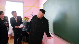 Kim Jong Un berbincang dengan para staf sekolah saat mengunjungi Sekolah Dasar Anak Yatim di Pyongyang (2/2). (AFP Photo / KCNA VIA KNS / STR)