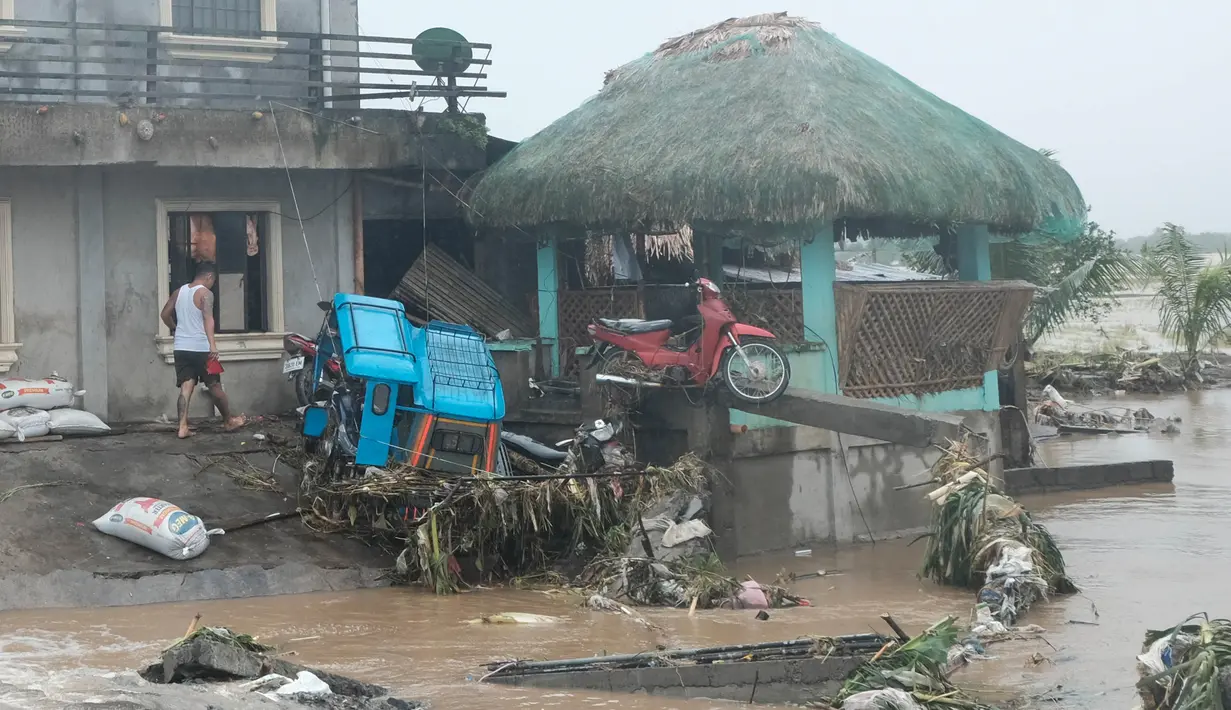 Seorang pria berjalan melewati kerusakan yang disebabkan oleh banjir bandang pada Kamis 24 Oktober 2024 di kota Libon, provinsi Albay, Filipina. (AP Photo/John Michael Magdasoc)