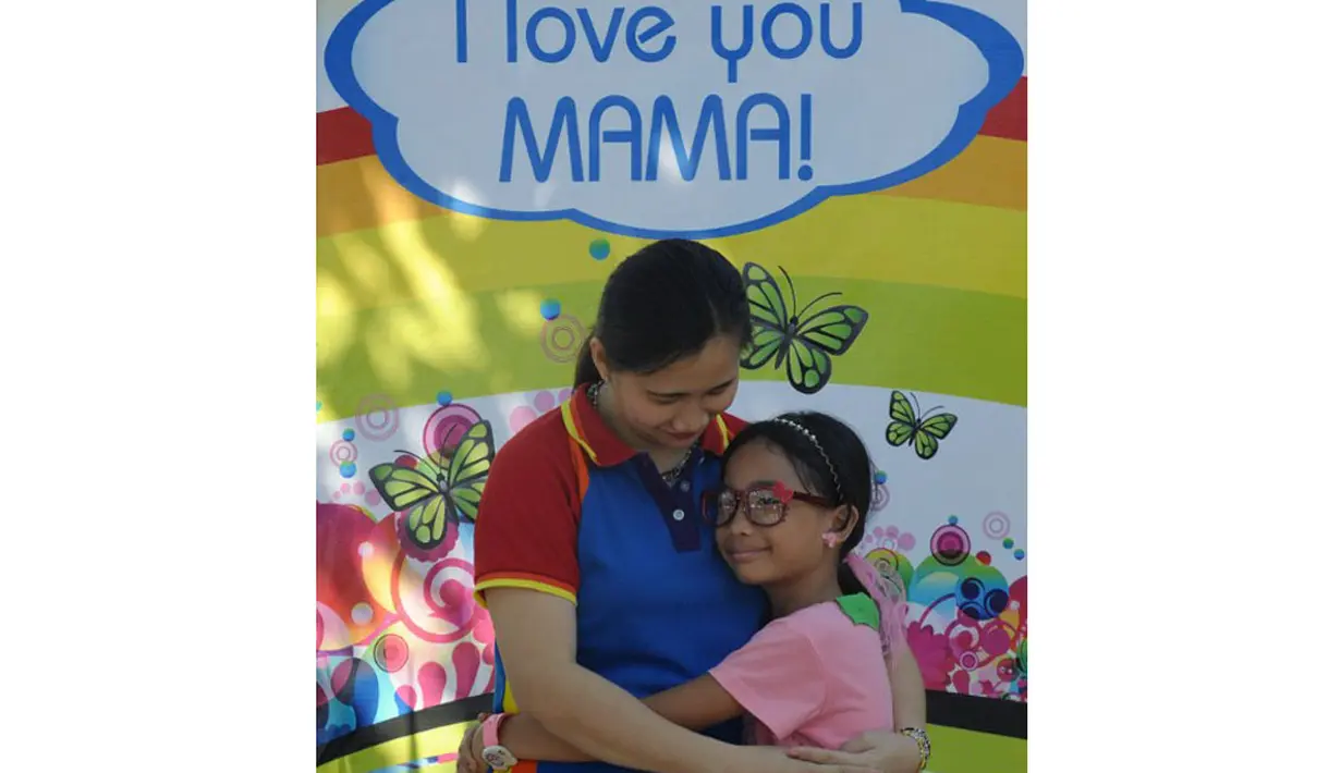 Dengan penuh kasih sayang, seorang ibu dan putrinya berpose di depan poster selama acara Hari Ibu yang diadakan di sebuah taman di pinggiran kota Manila, Filipina (11/5/2014). (AFP PHOTO/Jay Directo)