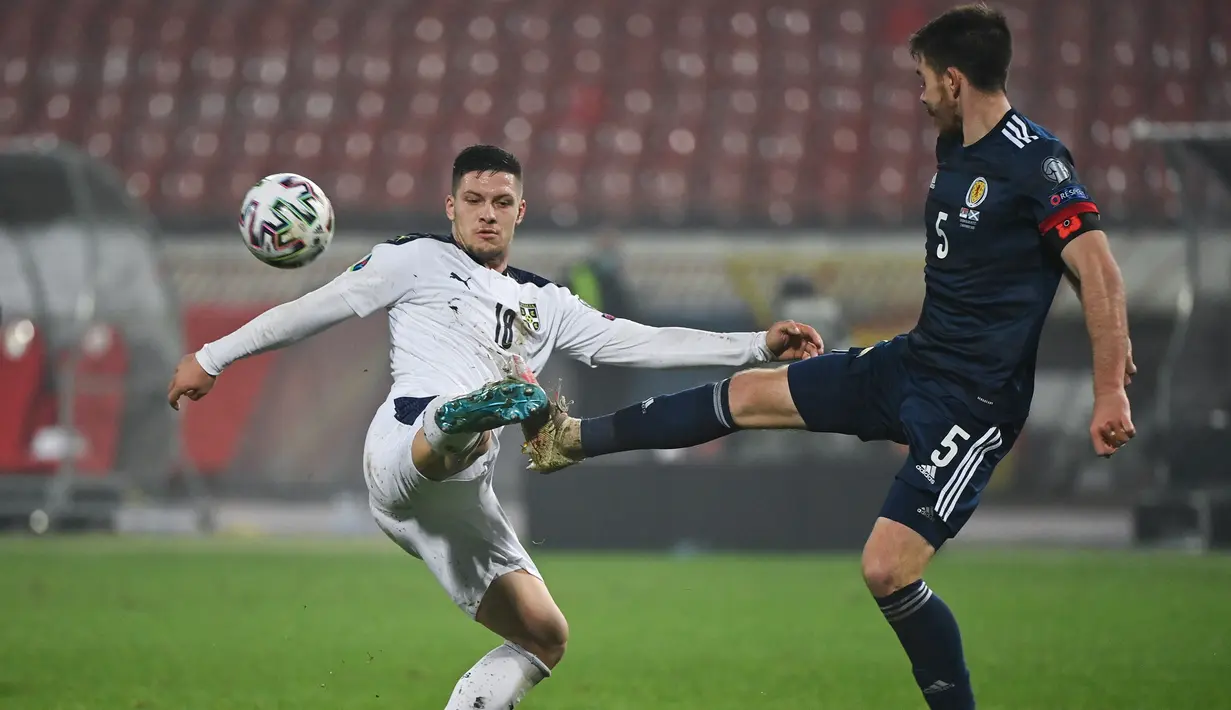 Penyerang Serbia, Luka Jovic, berebut bola dengan bek Skotlandia, Declan Gallagher, pada babak playoff Piala Eropa 2020 di Red Star Stadium, Jumat (13/11/2020) dini hari WIB. Skotlandia menang 5-4 atas Serbia lewat adu penalti. (AFP/Andrej Isakovic)