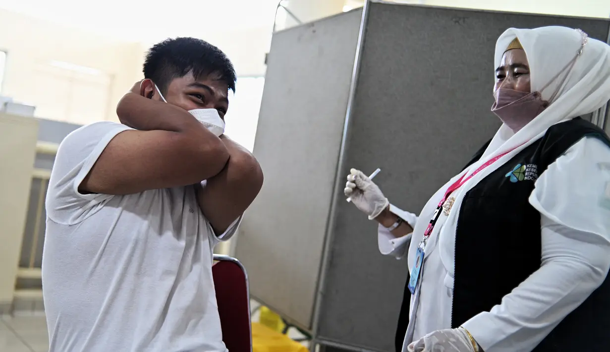 Reaksi seorang siswa SMA saat menerima dosis vaksin virus corona COVID-19 Pfizer di Rumah Sakit Zainoel Abidin, Banda Aceh, Aceh, Selasa (9/11/2021). Vaksinasi COVID-19 di kalangan warga Kota Banda Aceh tembus 80 persen. (CHAIDEER MAHYUDDIN/AFP)