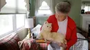 Mary Derr (93) menggendong robot kucing yang dipanggil "Buddy" di rumahnya, South Kingstown di Rhode Island, 1 Desember 2017. Robot kucing ini bisa bergerak, mengeong dan mendengkur seperti kucing hidup pada umumnya. (AP/Stephan Savoia)