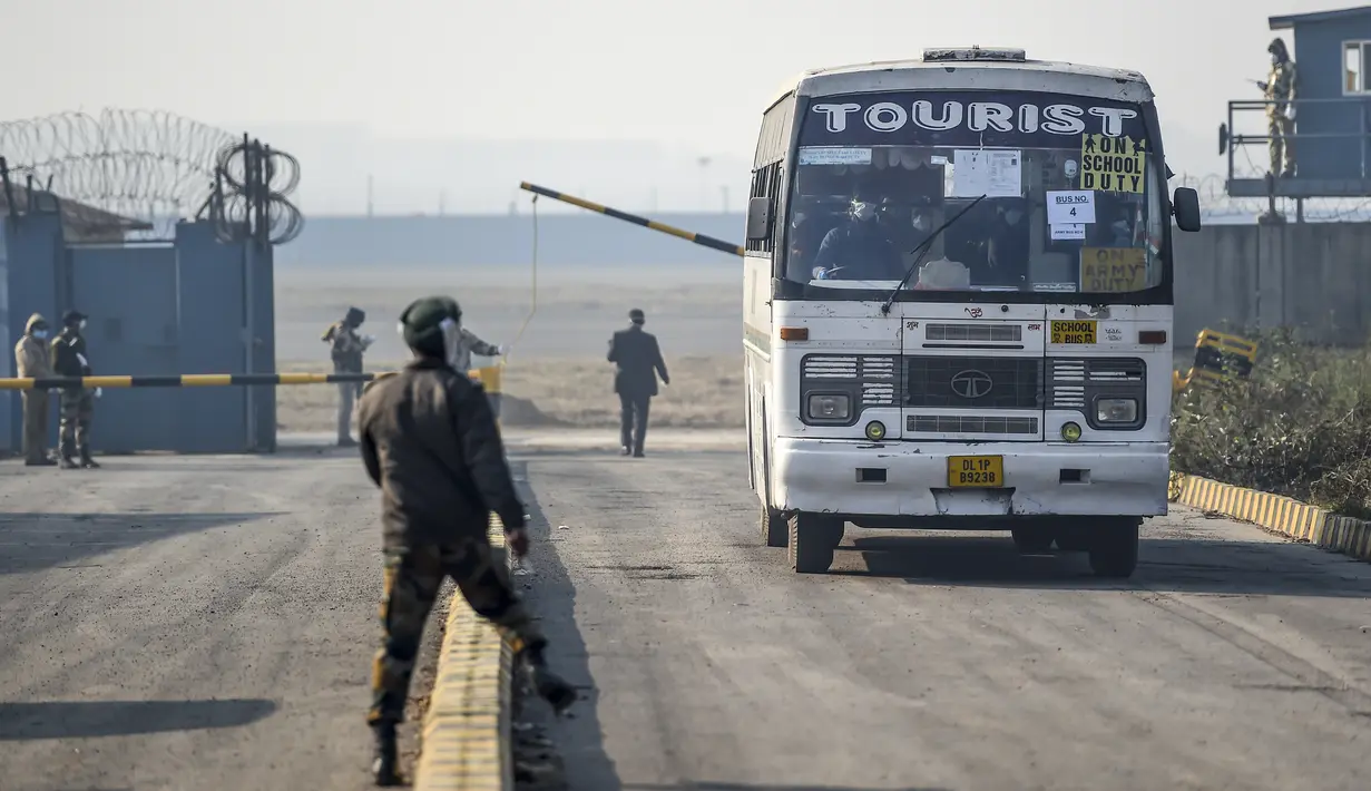 Petugas keamanan berjaga ketika warga negara India diangkut dengan bus keluar dari Bandara Internasional Indira Gandhi setelah dievakuasi dari kota Wuhan di Cina, di New Delhi (1/2/2020). (AFP/Money Sharma)