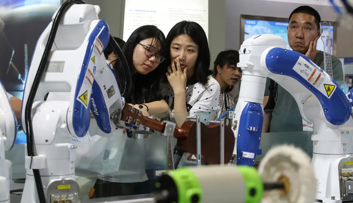 Pengunjung melihat robot buatan Tianji ketika memainkan gitar selama China International Robot Show di Shanghai (10/7/2019). Pameran yang menghadirkan robot-robot canggih ini diselenggarakan dari 10 sampai 13 Juli 2019. (AFP Photo/STR)