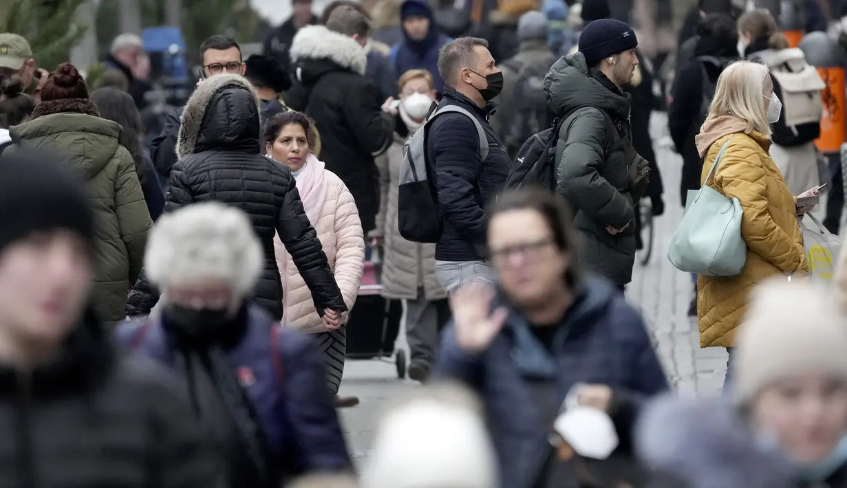 Orang-orang antre di depan sebuah toko sementara yang lain memadati jalan perbelanjaan di Berlin, Jerman, Selasa (21/12/2021). Jerman akan memutuskan pembatasan baru, yang kemungkinan dilakukan setelah Natal, yang bertujuan memperlambat penyebaran Covid-19 varian baru omicron (AP Photo/Michael Sohn)