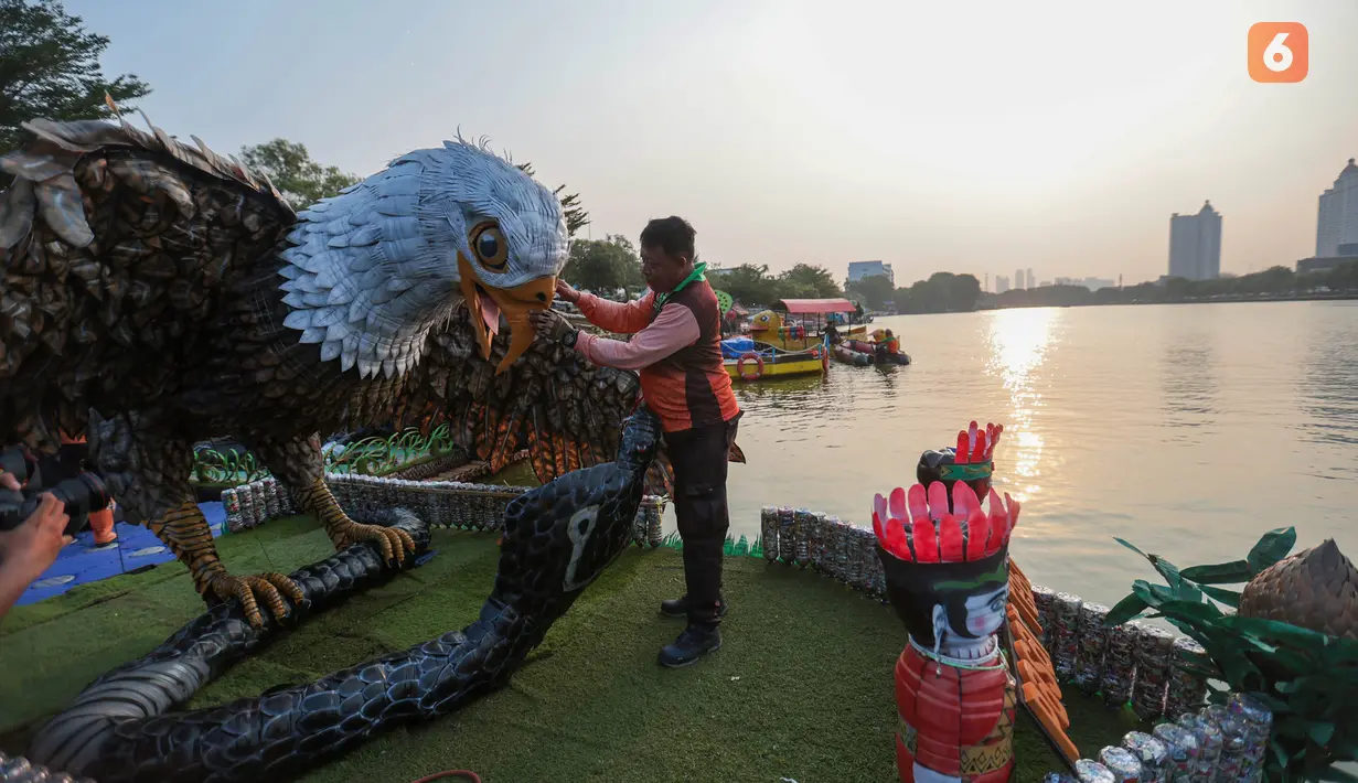 Petugas Pasukan Oranye DLH DKI Jakarta menyelesaikan pembuatan perahu berbahan botol plastik bekas di kawasan Danau Sunter Selatan, Jakarta Utara. Sebanyak 43 perahu dengan beragam desain unik disiapkan untuk meramaikan CiLung Fest 2026, Selasa (13/10/2026).(KLY/Budy Santoso)