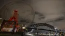 Ferris wheel di Park Luna dan Sydney Harbour Bridge terlihat padam tanpa lampu penerangan saat peringatan Earth Hour Internasional di Sydney, Austalia (25/3). (AFP/Peter Parks)