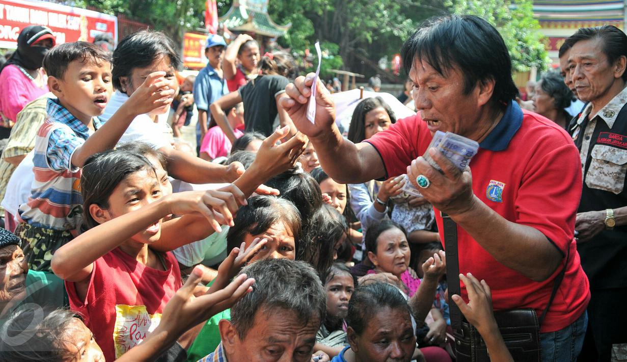 Petugas Vihara Dharma Bakti membagikan angpao dari umat Tionghoa yang datang untuk sembahyang jelang perayaan Imlek, Jakarta, (7/2/2016). Jelang Imlek, ratusan pengemis penuhi Vihara Dharma Bhakti untuk mendapatkan angpao. (Liputan6.com/Yoppy Renato)