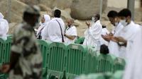 Polisi Saudi berjaga di depan jemaah Muslim yang sedang berdoa di Arafah selama ibadah haji di luar kota suci Mekah, Arab Saudi (19/7/2021). Sekitar 60 ribu jemaah haji mulai memadati kawasan Arafah, pada Senin pagi 9 Dzulhijjah 1442 Hijriah atau bertepatan pada 19 Juli 2021. (AP Photo/Amr Nabil)