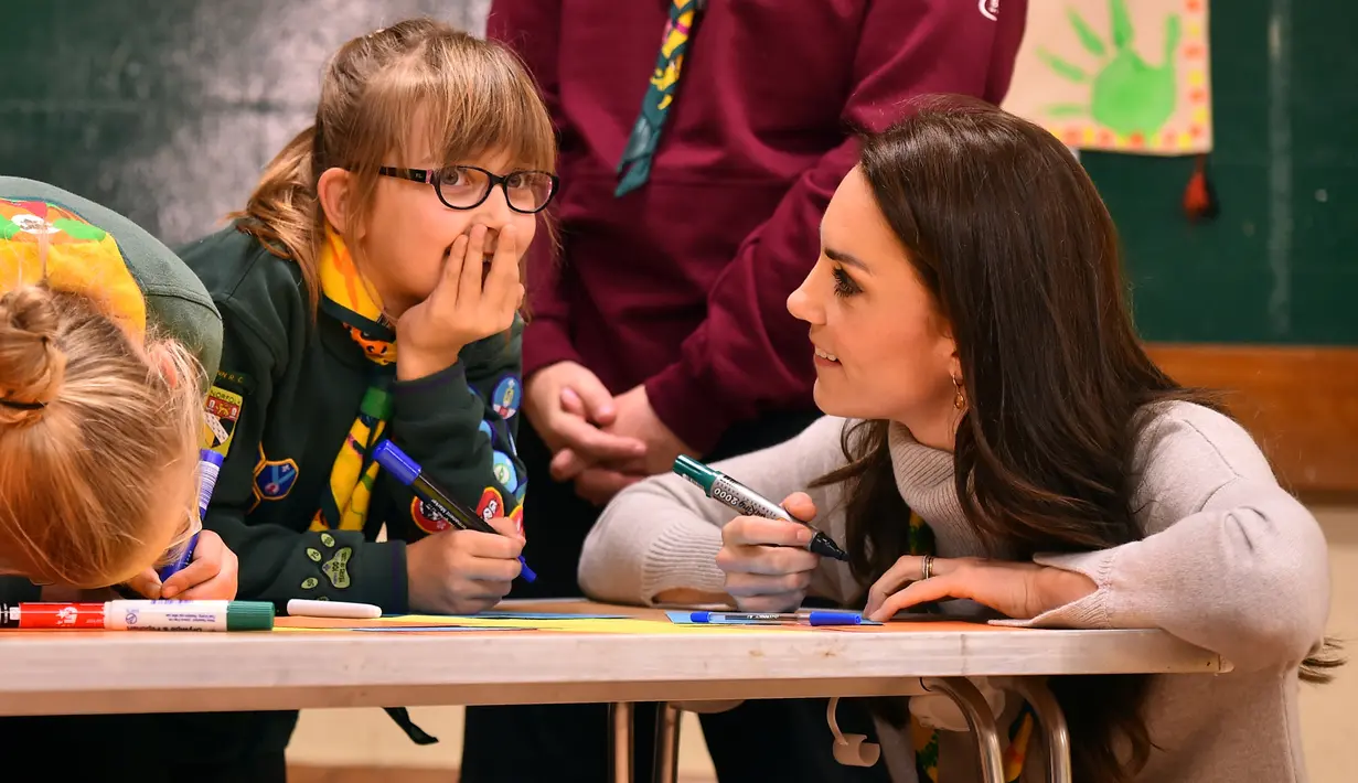 Kate Middleton berbincang dengan seorang anak saat mengikuti acara Cub Scout Pack di Kings Lynn, Inggris (14/12). Kehadiran Kate bertujuan untuk mengkampanyekan gerakan Pramuka di Inggris. (Reuters/Ben Stansall/Pool)