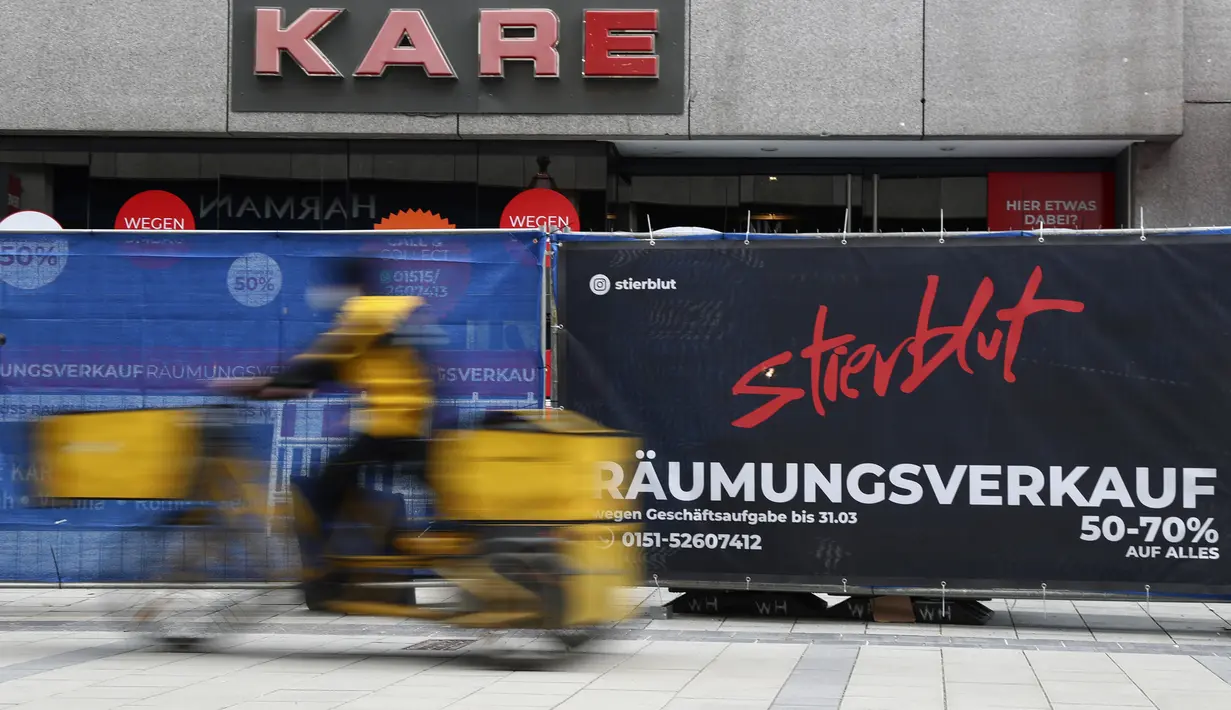Seorang tukang pos melewati toko yang tutup di pusat kota Munich, Jerman, Selasa (23/3/2021). Jerman memperpanjang tindakan pengunciannya sebulan lagi. (AP Photo/Matthias Schrader)