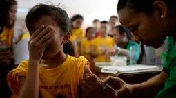 Siswi menutup mukanya saat petugas menyuntikkan vaksin anti-dengue di Sekolah Dasar Parang di Marikina, sebelah barat Manila, Senin (4/4). Filipina telah menyuntikkan vaksin pertama di dunia untuk penyakit DBD itu kepada 1 juta pelajar. (NOEL CELIS/AFP)