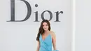 Miranda Kerr tampil dramatis sekaligus playful dengan gaun biru satin asimetris yang dihiasi pita besar di pinggang. Menampilkan rok tulle abu-abu di baliknya, dipadukan heels berhias bunga metalik [dok. Dior]