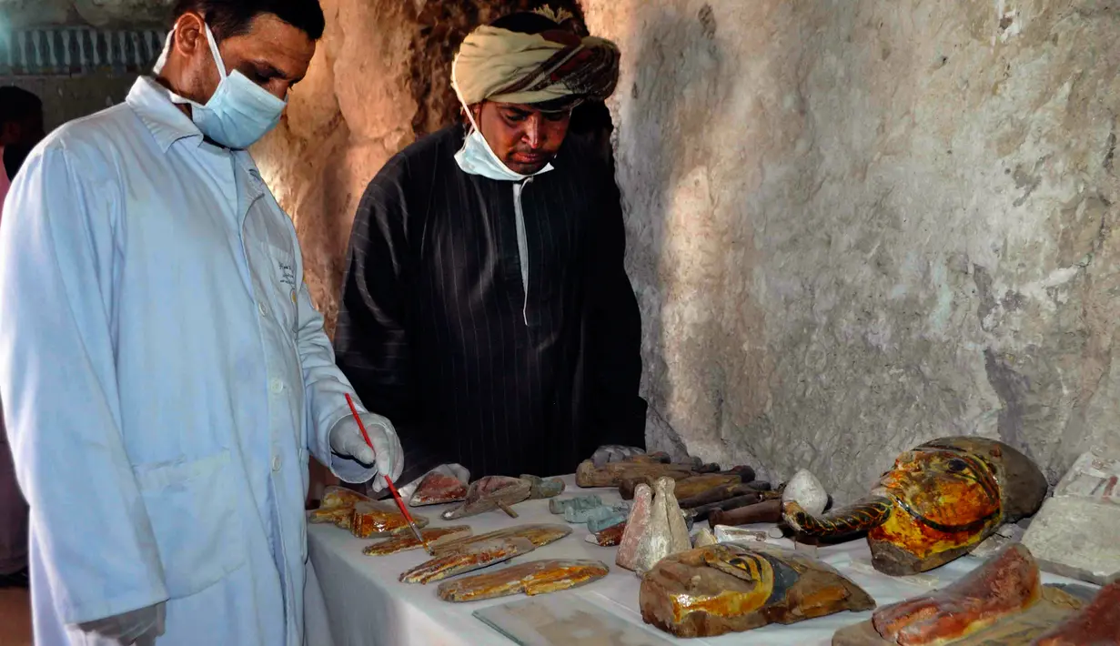 Arkeolog Mesir mengamati sejumlah artefak yang ditemukan di sebuah pemakaman berumur 3.500 tahun, sebelah selatan kota Luxor, Selasa (18/4). Area pemakaman kuno itu milik seorang bangsawan Mesir bernama Userhat yang juga seorang hakim. (STRINGER/AFP)