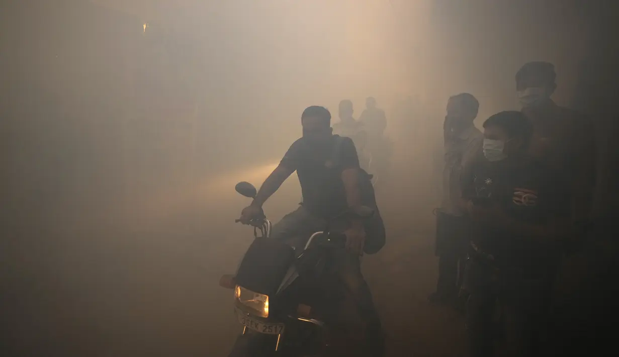 Komuter berjalan melewati asap dari fogging di daerah padat penduduk di New Delhi, India, Rabu (27/10/2021). New Delhi telah melaporkan ratusan kasus demam berdarah, dengan lebih dari 200 kasus baru dalam seminggu terakhir, menurut laporan yang dirilis pada hari Senin. (AP Photo/Manish Swarup)