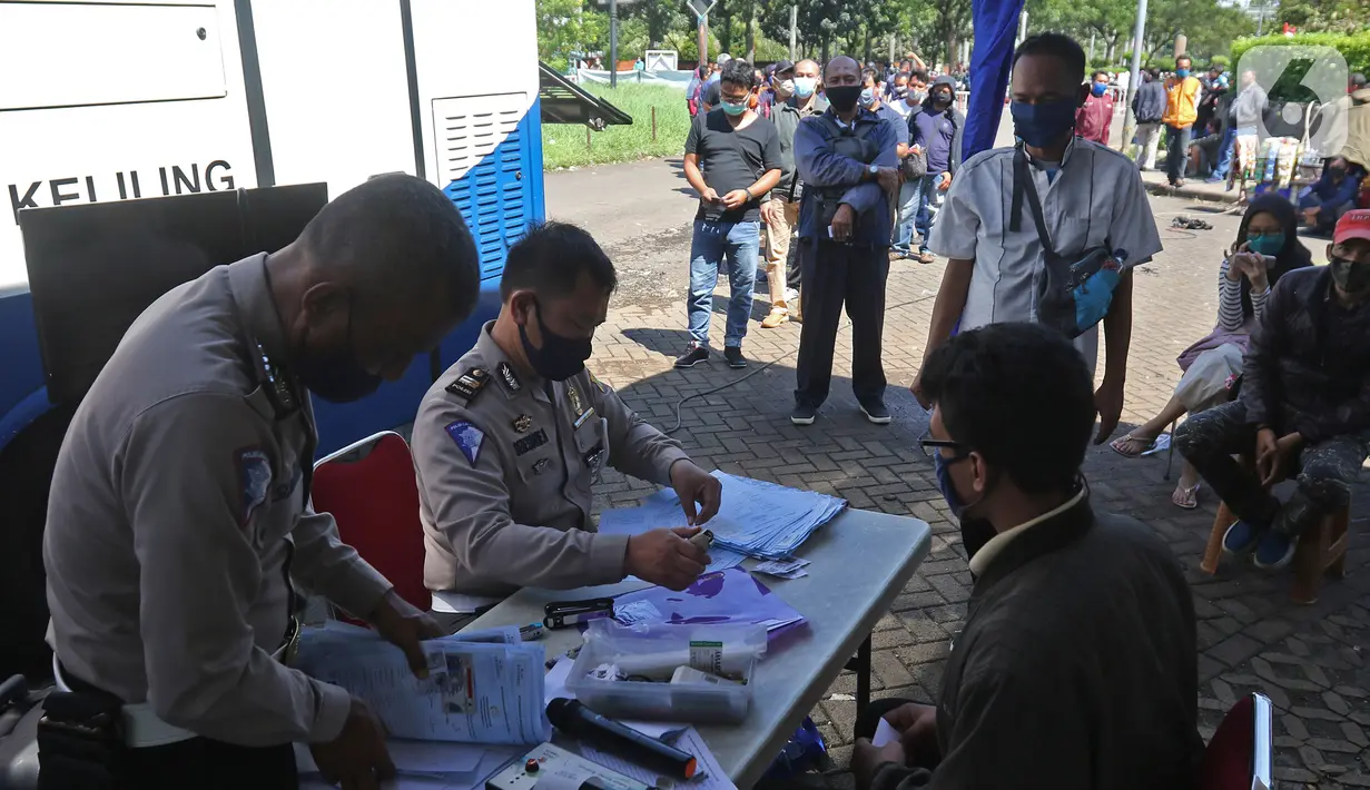 Petugas polisi melayani warga yang mengurus Surat Izin Mengemudi (SIM) di mobil layanan SIM Keliling Masjid At-Tin Jakarta, Kamis (4/6/2020). Direktorat Lalu Lintas Polda Metro Jaya mengoperasikan kembali layanan mobil SIM Keliling untuk mengantisipasi antrean pemohon. (Liputan6.com/Herman Zakharia)