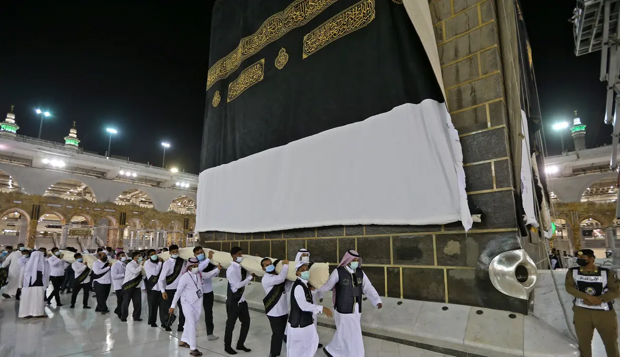 Petugas saat mengganti kain penutup Ka'bah (Kiswah) dengan yang baru di Masjidil Haram, kota suci Makkah, Arab Saudi (18/7/2021). Menjelang puncak ibadah haji 1442 H, petugas Masjidil Haram melakukan penggantian kain penutup Ka'bah lama dengan Kiswah yang baru. (AFP Photo)