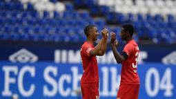 Pemain Augsburg, Felix Uduokha dan Reece Oxford merayakan kemenangan atas Schalke 04 pada laga Bundesliga di Veltins-Arena, Minggu (24/5/2020). Augsburg menang dengan skor 3-0 atas Schalke 04. (AP/Martin Meissner)