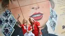 Penggemar Taylor Swift berswafoto dengan latar belakang mural sang penyanyi yang dibuat oleh seniman jalanan MurWalls, di luar Stadion Wembley, London, Kamis (15/8/2024). (JUSTIN TALLIS / AFP)