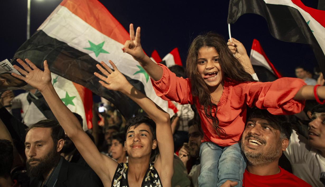 Pendukung Presiden Suriah Bashar Assad mengibarkan bendera nasional saat mereka merayakan kemenangannya di Omayyad Square, di Damaskus, Kamis (27/5/2021). Bashar al-Assad terpilih kembali untuk masa jabatan keempat sebagai presiden Suriah yang dilanda perang. (AP Photo/Hassan Ammar)