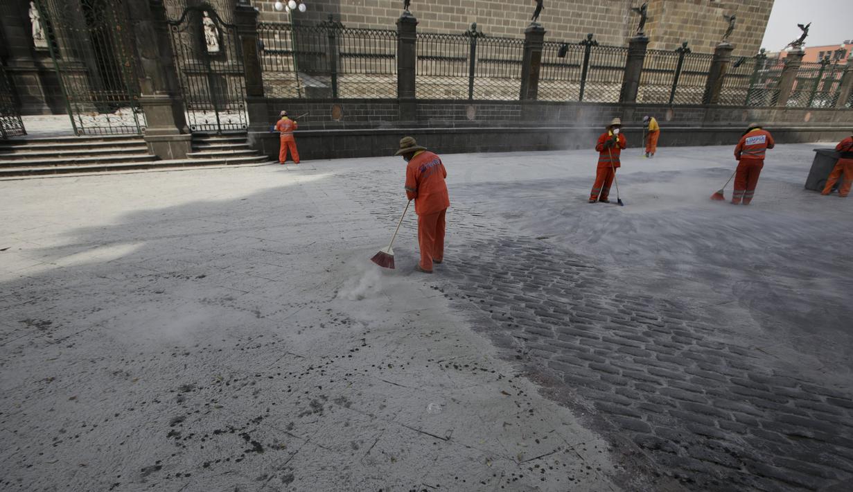 Sejumlah Petugas memakai masker membersihkan jalan yang tertutup abu setelah letusan gunung berapi Popocatepetl di Puebla, Meksiko, (18/4).  Pihak berwenang meminta warga unutk menjauh setidaknya 12 kilometer dari puncak gunung. (REUTERS/Imelda Medina)