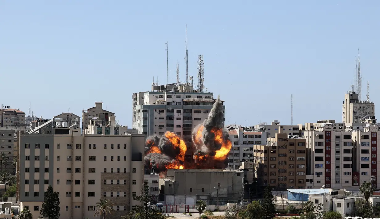 Bola api meletus dari gedung yang menampung berbagai media internasional, termasuk The Associated Press, setelah serangan udara Israel di Kota Gaza, Sabtu (15/5/2021). Serangan terjadi satu jam usai militer Israel memerintahkan orang-orang untuk mengungsi dari gedung. (Mahmud Hams/Pool Photo via AP)