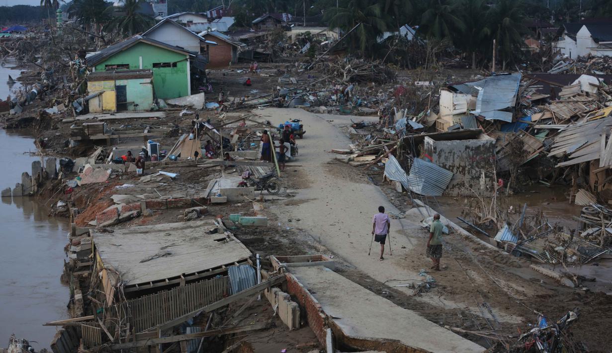 Data BPBD juga mencatat, korban meninggal dunia di Kabupaten Aceh Tamiang sebanyak 42 orang. Tampak dalam foto, para penyintas berjalan di area terdampak banjir bandang di Aceh Tamiang, Sumatera, Kamis 4 Desember 2025. (AP Photo/Binsar Bakkara)