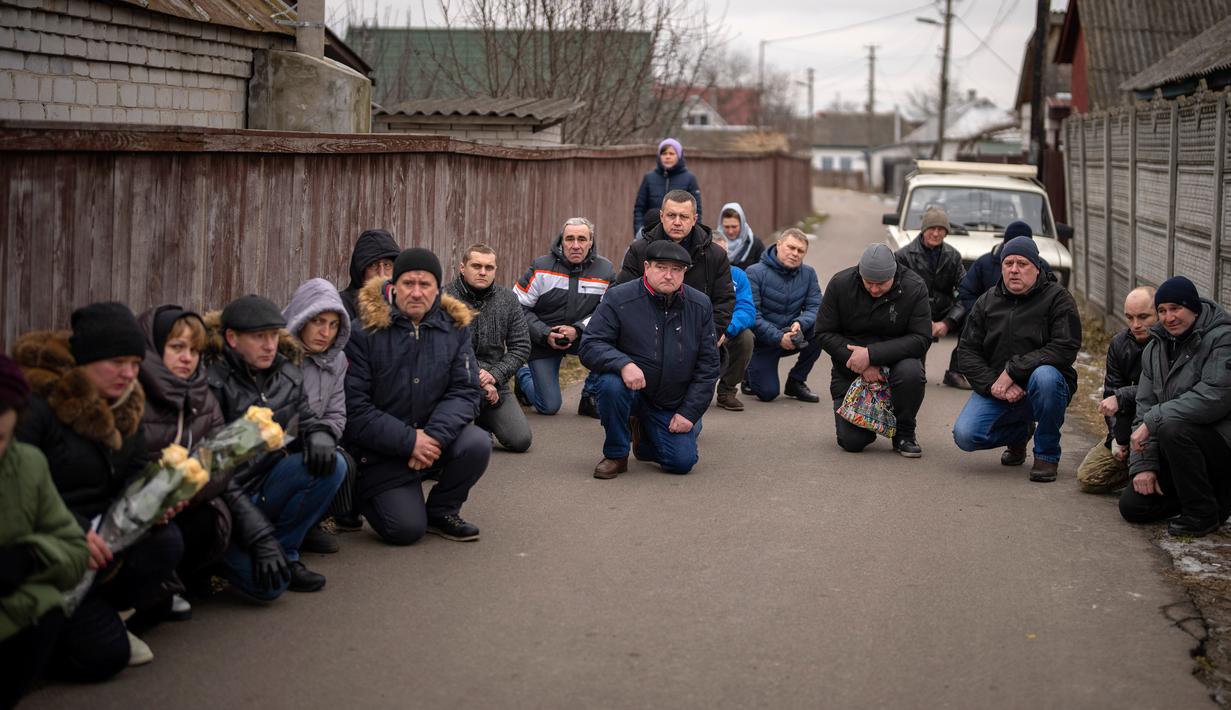 Para pelayat berlutut menunggu peti mati Oleksandr Maksymenko (38) lewat saat pemakamannya di kampung halamannya di Kniazhychi, sebelah timur Kyiv, Ukraina, 13 Februari 2023. Oleksandr Maksymenko, seorang warga sipil yang menjadi sukarelawan di angkatan bersenjata Ukraina, tewas dalam pertempuran di daerah Bakhmut. (AP Photo/Emilio Morenatti)
