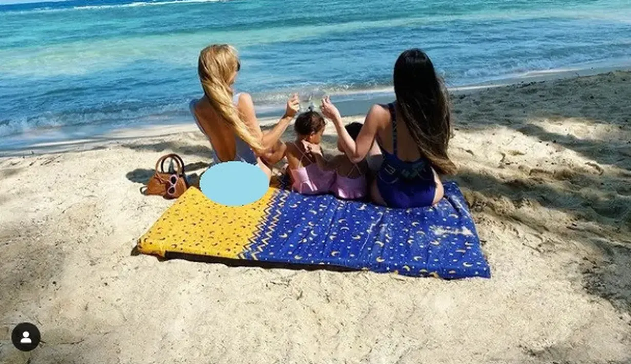 Varsha Strauss Adhikumoro, bersama anak dan temannya berpiknik di pinggir pantai. Mereka menggelar tikar, dan menikmati indahnya laut biru. (Foto: Instagram/@varshaadhikumoro)