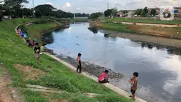 Anak-anak bermain di sekitar bantaran Kanal Banjir Timur (KBT), kawasan Cipinang Muara, Jakarta, Selasa (16/6/2020). Sebagian besar warga masih mengabaikan protokol kesehatan dengan tidak menjaga jarak serta tanpa menggunakan masker. (Liputan6.com/Immanuel Antonius)
