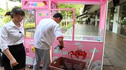 Pekerja restoran memasukkan kepiting ke dalam mesin capit di Singapura, 23 Oktober 2019. Pengunjung bisa mencoba menangkap kepiting hidup dari mesin capit itu dengan kupon seharga US$ 5 dan jika berhasil, restoran akan memasakkannya secara  gratis. (Roslan RAHMAN / AFP)