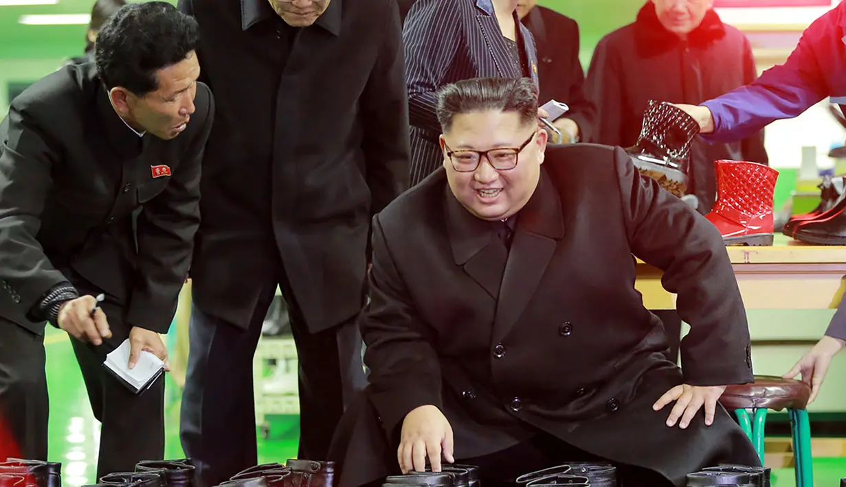 Pemimpin Korea Utara, Kim Jong-Un melihat sepatu saat mengunjungi pabrik sepatu Wonsan, Korea Utara (3/12). (Photo by KCNA VIA KNS / various sources / AFP)