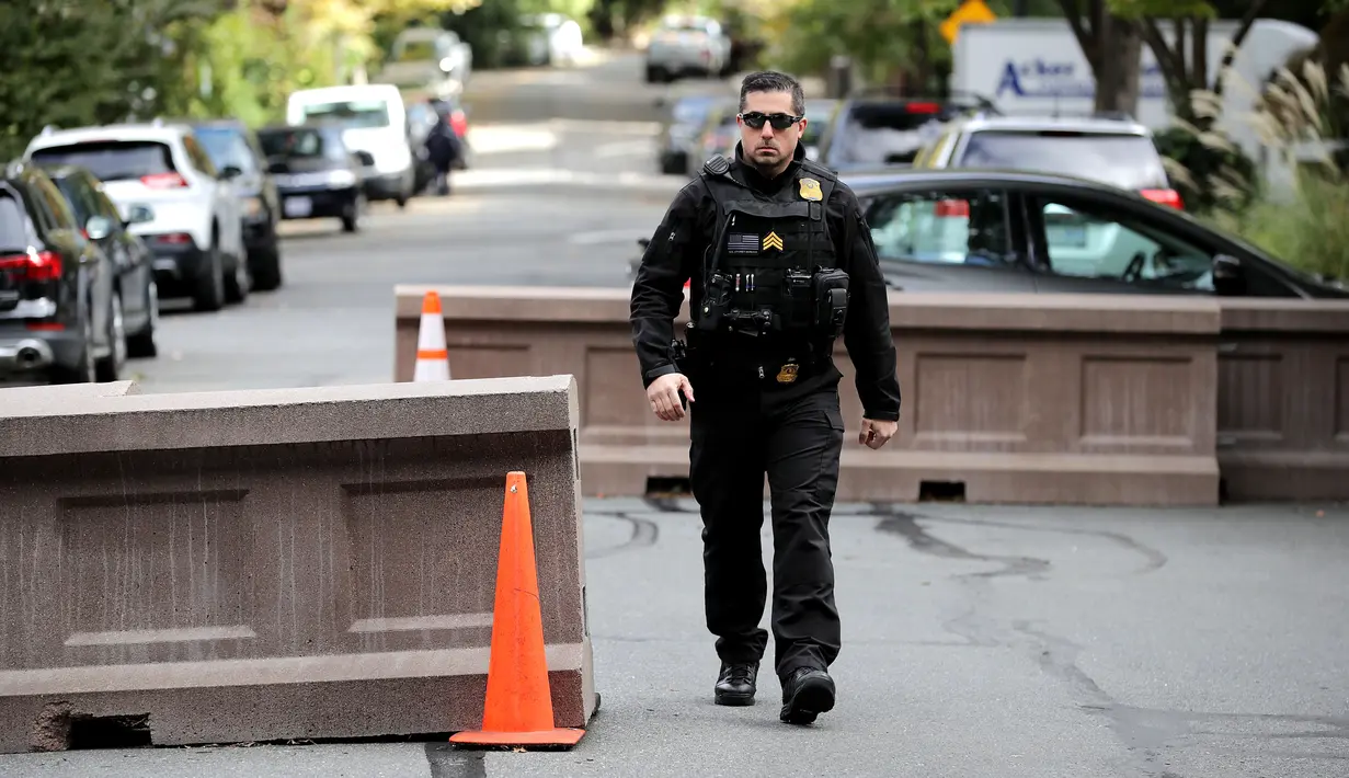 Petugas Secret Service berjaga di ujung jalan menuju rumah mantan Presiden AS, Barack Obama di Washington, Rabu (24/10). Dinas Rahasia AS telah menggagalkan pengiriman paket berisi bahan peledak ke rumah Barack Obama. (CHIP SOMODEVILLA/GETTY IMAGES/AFP)