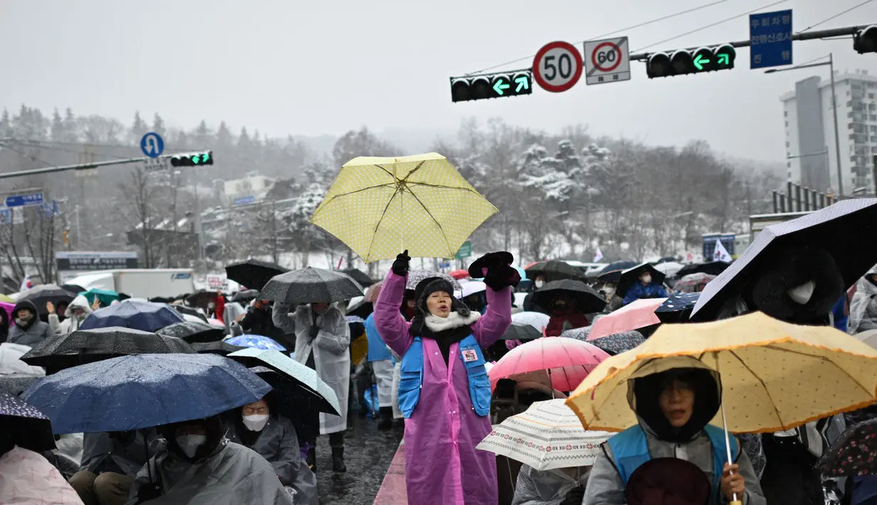 Para pengunjuk rasa bertahan di tengah hujan salju tebal di Seoul, Ibu Kota Korea Selatan, Minggu (5/1/2024), untuk menentang penangkapan Presiden Yoon Suk Yeol yang dimakzulkan. (Philip FONG/AFP)