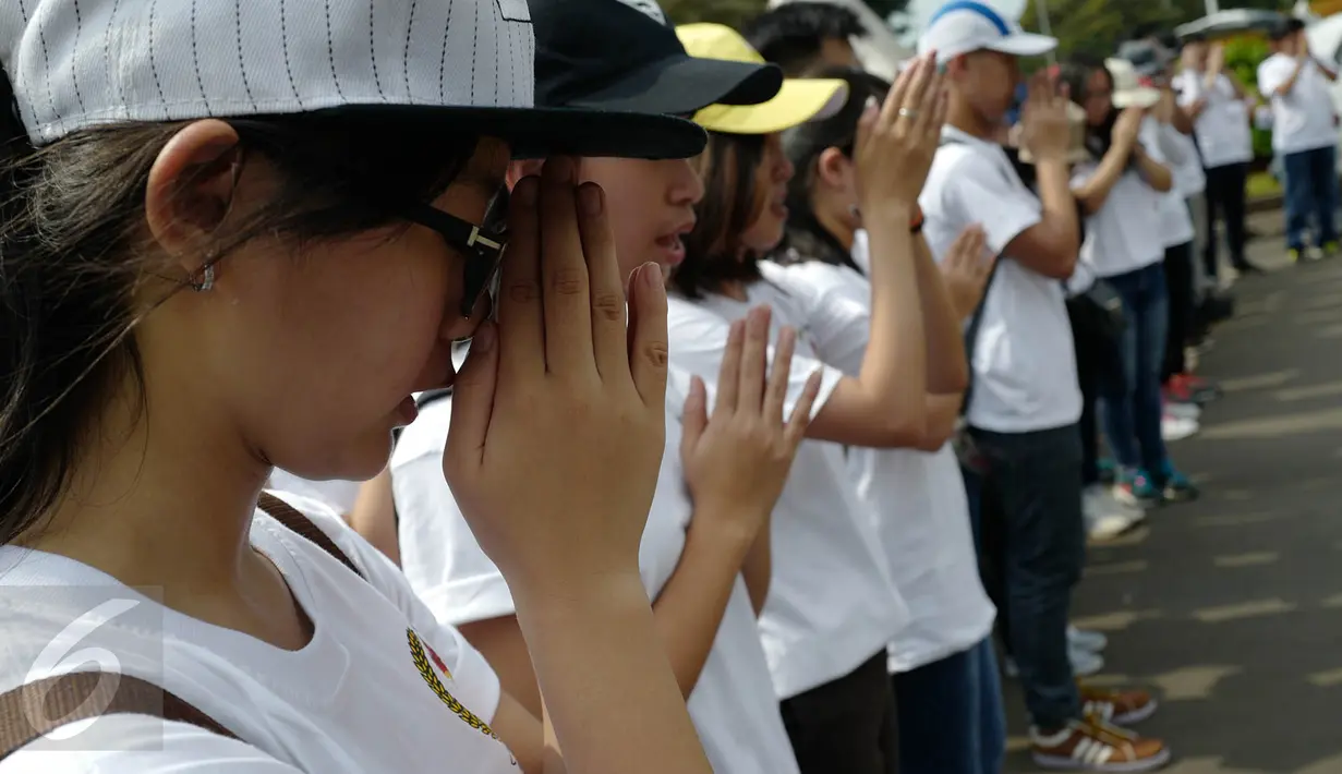 Massa yang tergabung dalam Generasi Muda Buddhis Indonesia (Gemabudhi) berdoa sebelum membagikan bunga kepada pengguna jalan di depan Istana Negara, Jakarta, Sabtu (6/1). (Liputan6.com/Immanuel Antonius)
