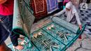 Pekerja menggulung karpet masjid pesanan pembeli di sebuah toko di kawasan Tanah Abang, Jakarta, Kamis (16/3/2023). (Liputan6.com/Angga Yuniar)