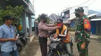 Nampak petugas TNI - Polres Garut, tengah memberikan masker kepada masyarakat saat pelaksaan operasi yustisi pencegahan Covid-19 di Garut, Jawa Barat. (Liputan6.com/Jayadi Supriadin)