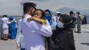 Seorang perwira angkatan laut memeluk seorang anak Upacara Tabur Bunga di geladak heli KRI Dr. Soeharso 990 di perairan utara Pulau Bali, Bali, Jumat (30/4/2021). Upacara itu digelar sebagai penghormatan terakhir bagi awak KRI Nanggala 402 yang gugur dalam medan tugas. (Juni Kriswanto/AFP)