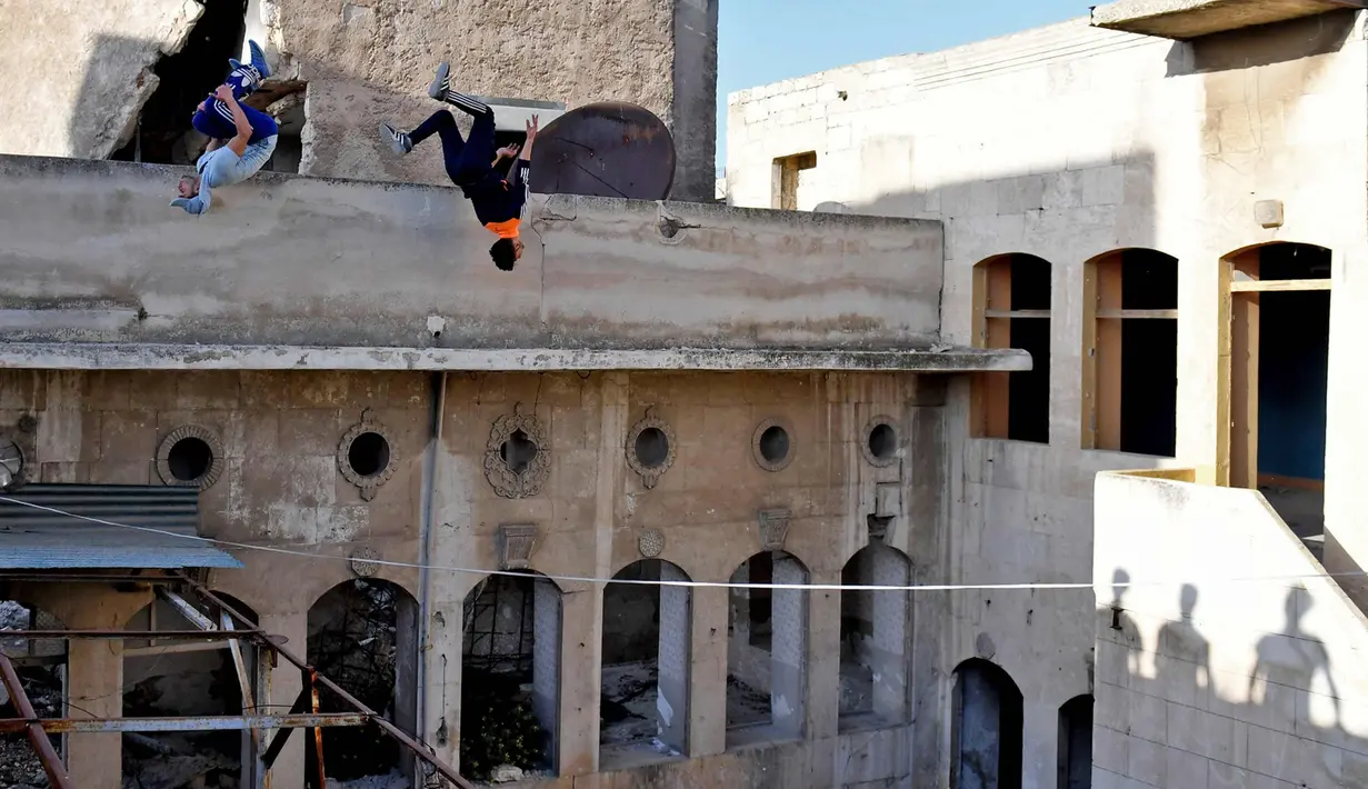 Dua pemuda melompat berlatih parkour di Aleppo, Suriah, (7/4). Setelah pemerintah Suriah mengambil alih kendali penuh Aleppo dari pasukan pemberontak Desember 2016, beberapa pemuda kini menyalurkan hobinya, yaitu parkour.  (AFP Photo/George Ourfalian)
