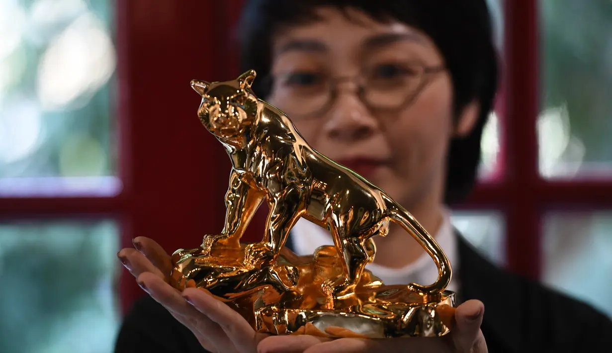 Seorang perempuan berpose dengan model harimau berlapis emas, menjelang Tahun Baru Imlek, yang ditandai sebagai Tahun Macan Air di Hanoi, pada 19 Januari 2022. Di Vietnam, perayaan Tahun Baru China disebut Tet yang merupakan salah satu perayaan paling penting masyarakat di sana. (Nhac NGUYEN/AFP)