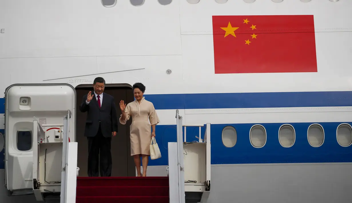 Presiden China Xi Jinping dan istrinya Peng Liyuan melambaikan tangan saat mereka turun dari pesawat setibanya di Bandara Internasional Ngurah Rai menjelang KTT G20 di Bali, Senin (14/11/2022). Xi Jinping, tiba di Pulau Bali dengan menggunakan pesawat kepresidenan Air China, Senin (14/11), untuk mengikuti KTT G20 di Nusa Dua, Kabupaten Badung, Bali, mulai esok. (Ajeng Dinar Ulfiana/Pool Photo via AP)