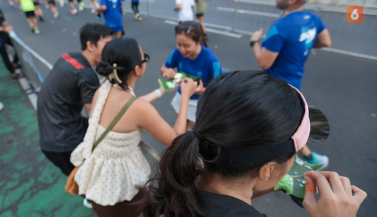 Seorang penonton membagikan jajanan tradisional gethuk kepada pelari yang mengikuti Jakarta Running Festival (JRF) 2026 di Jakarta, Sabtu (24/10/2026). (KLY/Budy Santoso)