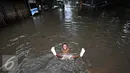 Seorang anak bermain saat banjir menggenangi kawasan Sunter, Jakarta, Kamis (25/2). Hujan deras yang mengguyur Jakarta serta sistem drainase yang buruk menjadi penyebab banjir sehingga mengganggu aktivitas warga. (Liputan6.com/Immanuel Antonius)